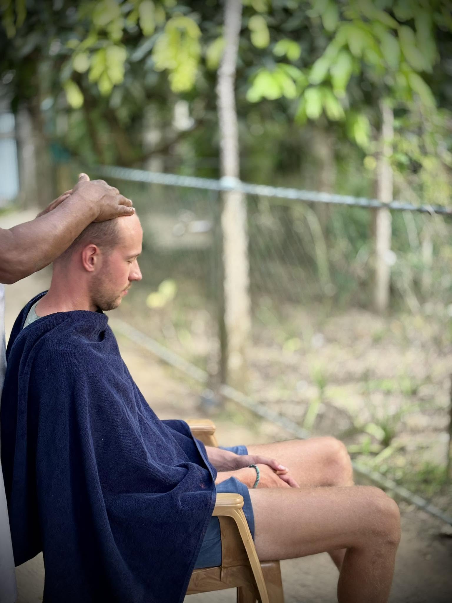 Guest receiving a traditional Ayurvedic head treatment outdoors